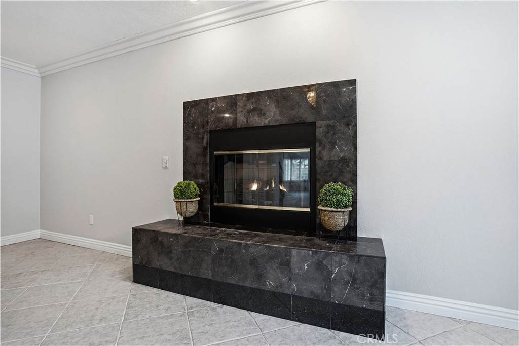 6568 Balzac Circle Riverside, CA 92506 - Photo 19 of 62 Gas fireplace tuns on by a swittch! Granite encased. Oversized travertine tiles are easy to clean. This family room area is in front of the downstairs primary bedroom. Crown molding above and below. Recessed lighting.