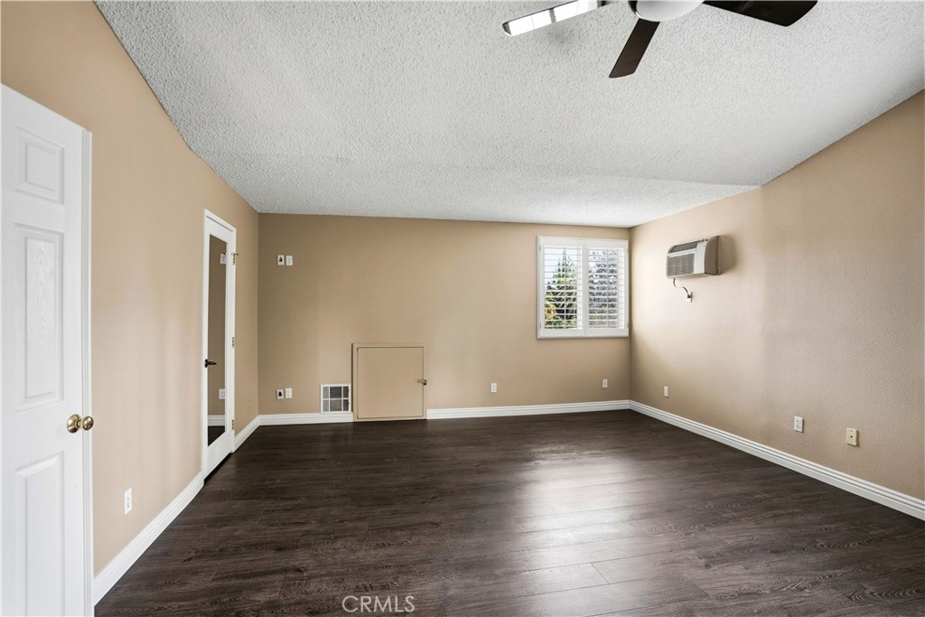 6568 Balzac Circle Riverside, CA 92506 - Photo 33 of 62 Primary bedroom upstairs is oversized. Room has mini-slpit for instant cold air as well as the ac. First of 2 walk-in closets is in the photo where the mirror closet door is. Secret attic acces door. Wood laminate flooring. Celing fan above.