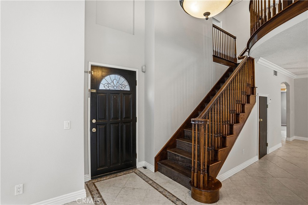 6568 Balzac Circle Riverside, CA 92506 - Photo 5 of 62 Exquisite front door with beveled glass sets the tone for this home! Custom wood staircase. Travertine patterns throughout in the flooring. Secret safe room under the stairway. Doorway in the far corner leads to your indoor laundry room, hallway closet, then the downstairs primary en-suite bedroom.