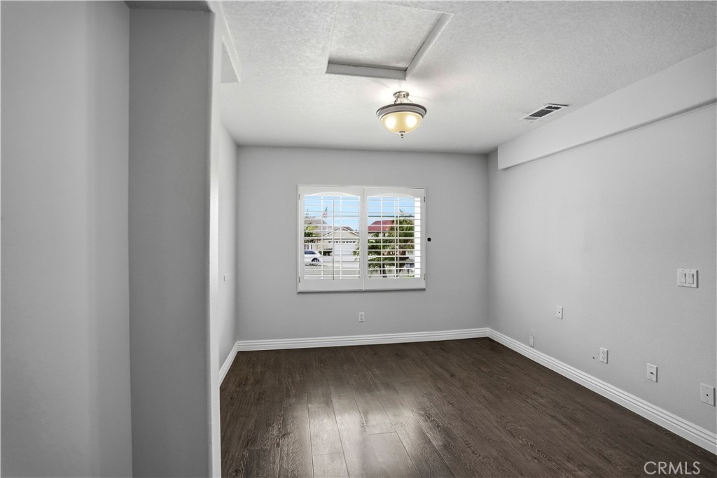 6568 Balzac Circle Riverside, CA 92506 - Photo 9 of 62 Downstairs Primary bedroom with wood laminate flooring. Window looks onto the cul-de-sac front yard. Primary bedroom has walk-in closet and en-suite bathroom.