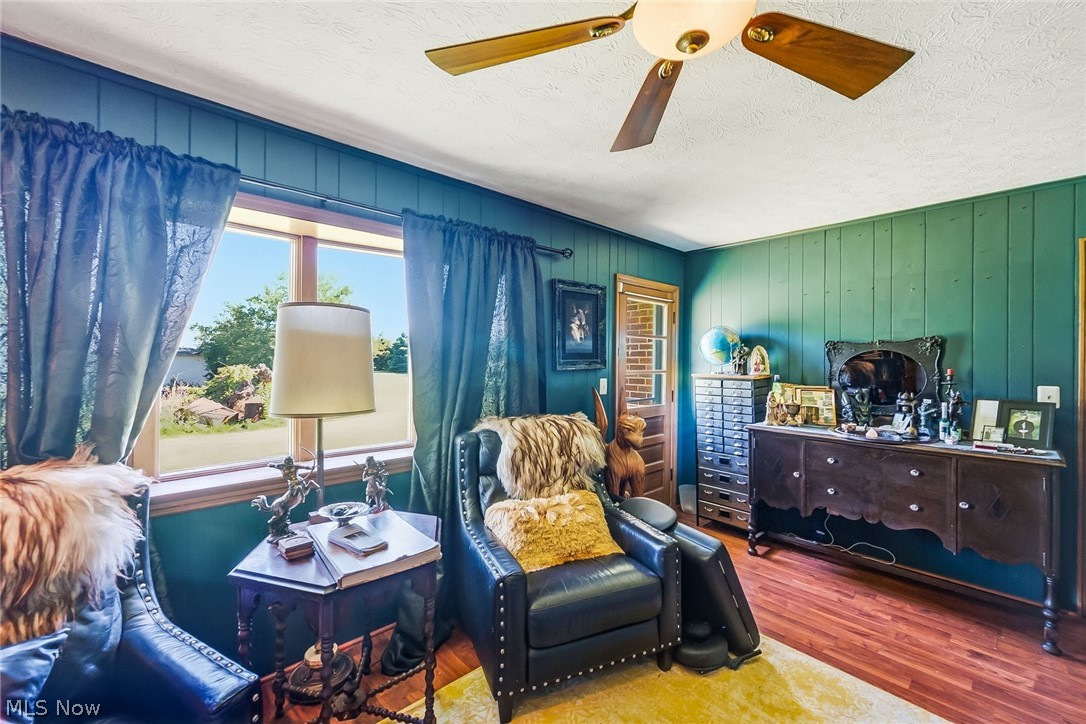 6890 Refugee Road Pickerington, OH 43147 - Photo 22 of 49 Room featuring rich green vertical paneling, wood-finish flooring, and a ceiling fan with light fixture