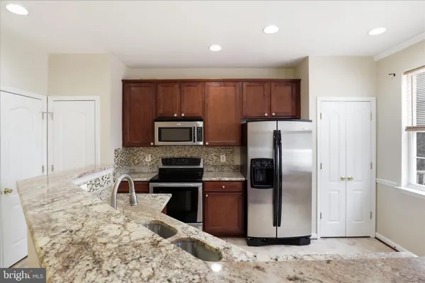 a kitchen with kitchen island granite countertop cabinets and stainless steel appliances