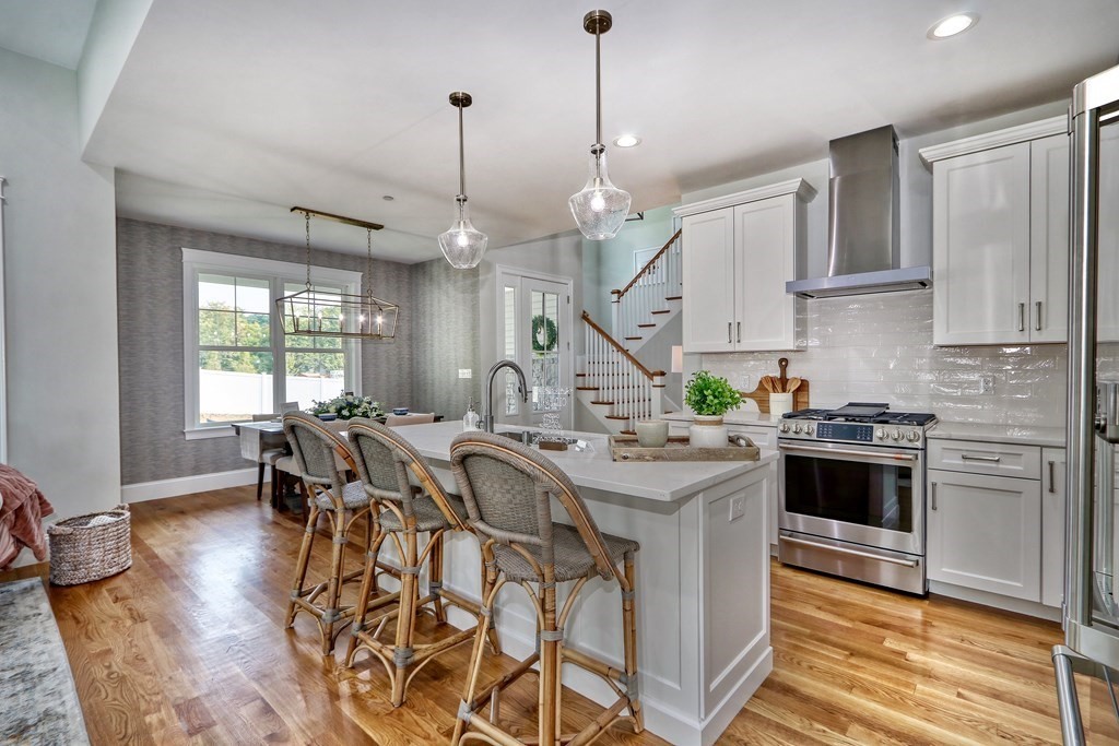 67 Rowell Road, Unit 67 Middleton , MA 01923 - Photo 10 of 40 a kitchen with stainless steel appliances granite countertop a stove a sink dishwasher a microwave oven with a dining table and chairs with wooden floor