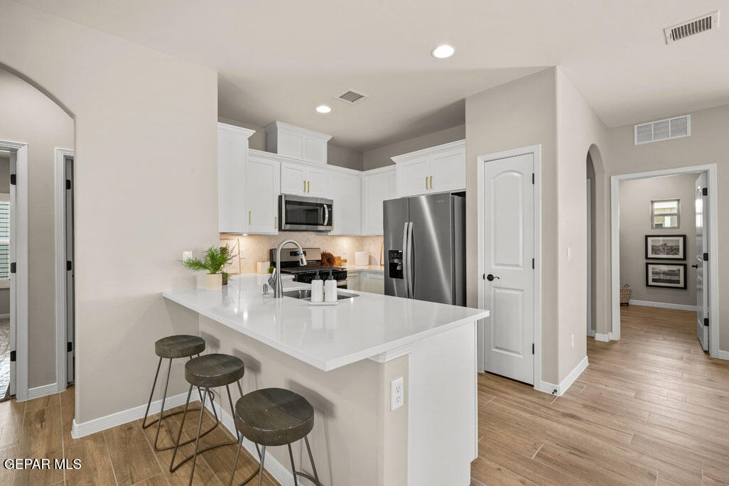 664 Paseo Musical Street El Paso, TX 79928 - Photo 17 of 50 a kitchen with stainless steel appliances a dining table chairs stove refrigerator and cabinets