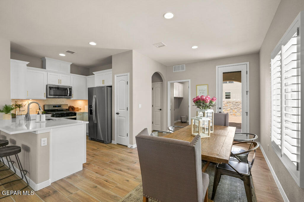 664 Paseo Musical Street El Paso, TX 79928 - Photo 20 of 50 a kitchen with stainless steel appliances kitchen island granite countertop a refrigerator a stove top oven a sink dishwasher and white cabinets with wooden floor
