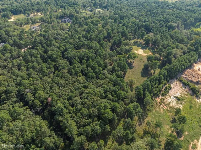 an aerial view of residential house with outdoor space and trees all around