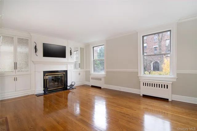 a view of an empty room with window fireplace and wooden floor