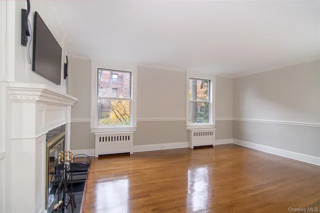 a view of empty room with fireplace and wooden floor