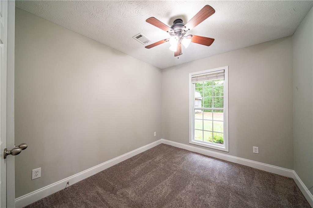 1927 Lee Road Salem, AL 36874 - Photo 37 of 45 Unfurnished room featuring dark colored carpet, a textured ceiling, and a ceiling fan