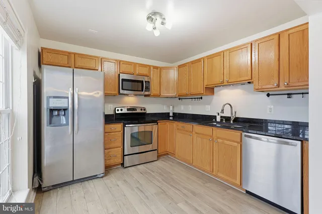 a kitchen with granite countertop a refrigerator stove top oven and sink