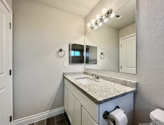 a bathroom with a granite countertop sink and a mirror