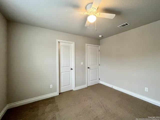 a view of an empty room and a chandelier fan