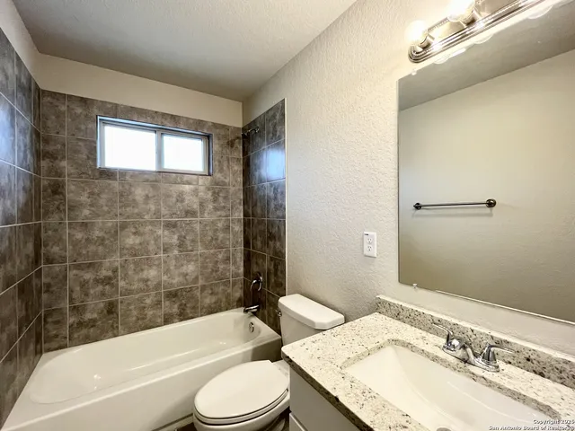 a bathroom with a granite countertop toilet sink and bathtub