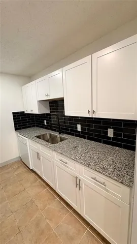 a kitchen with stainless steel appliances granite countertop a sink and a white cabinets