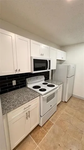 a kitchen with granite countertop white cabinets and white appliances