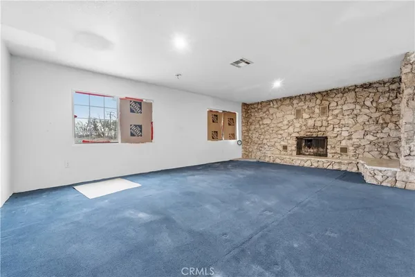 an empty room with windows and fireplace