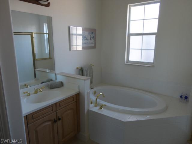 755 Regency Reserve Circle, Unit 5004 Naples, FL 34119 - Photo 17 of 24 a bathroom with a tub sink and mirror