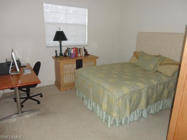 755 Regency Reserve Circle, Unit 5004 Naples, FL 34119 - Photo 22 of 24 a spacious bedroom with a bed a desk and chair