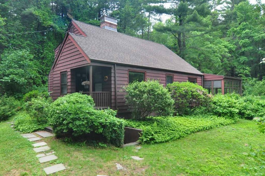 a view of a house with a yard plants and large tree