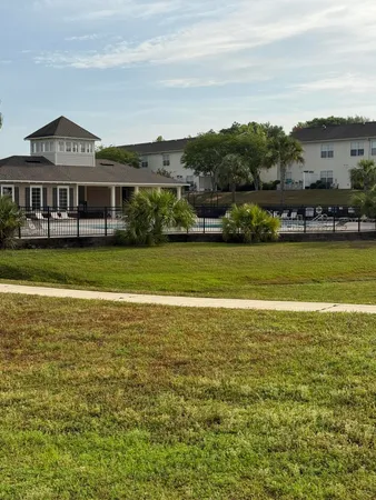 a view of a big house with a big yard and palm trees