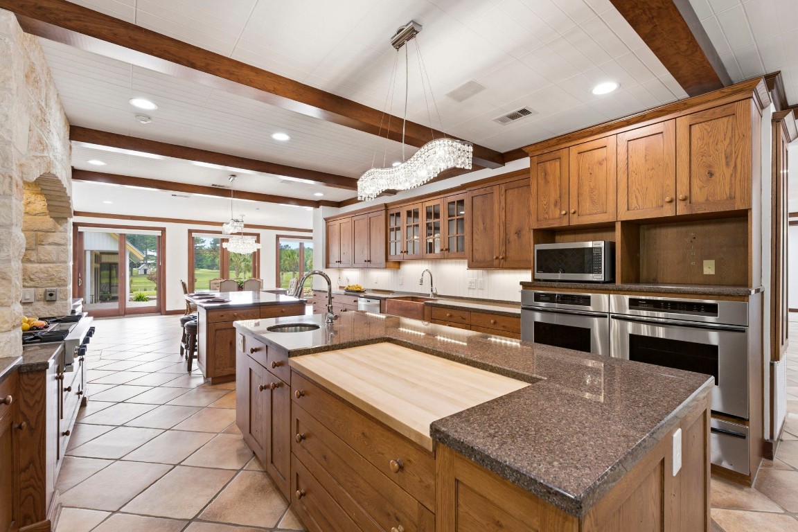 43 Pool Road Richards, TX 77873 - Photo 21 of 50 The kitchen flows seamlessly into the formal dining area, where large windows frame picturesque views of the backyard oasis, creating a bright and inviting atmosphere. Built-in fridge, 2 Sub-zero refrigerated drawers, custom chestnut oak cabinetry, built-in cutting board, pull-out spice racks, Brazilian granite countertops and more! Truly a culinary-inspiring kitchen!