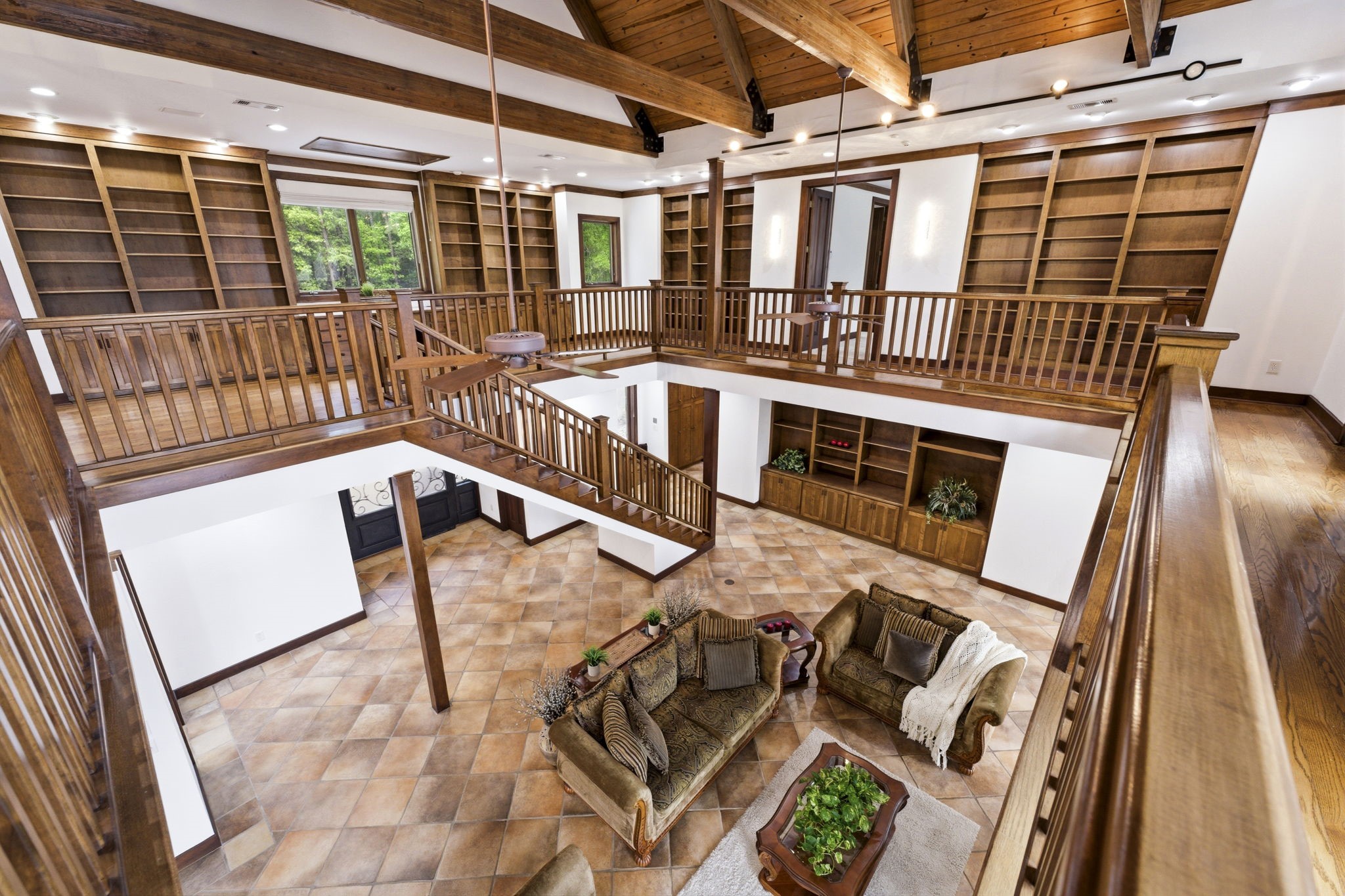 43 Pool Road Richards, TX 77873 - Photo 29 of 50 A warm wood second-story wraparound walkway, lined with built-in shelves and desk, overlooks the formal living area below, blending functionality with an airy, open connection to the space beneath.