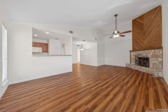 a view of empty room with wooden floor and fan