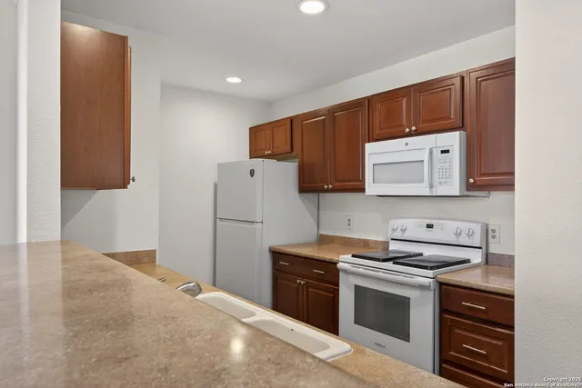 a kitchen with stainless steel appliances granite countertop a stove a sink and a refrigerator with wooden cabinets