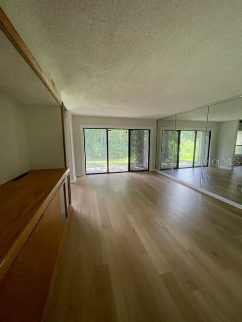 5466 Pine Creek Drive, Unit 2002 Orlando, FL 32811 - Photo 10 of 19 wooden floor in an empty room with a window