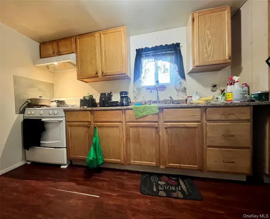 a kitchen with granite countertop a sink a stove and cabinets