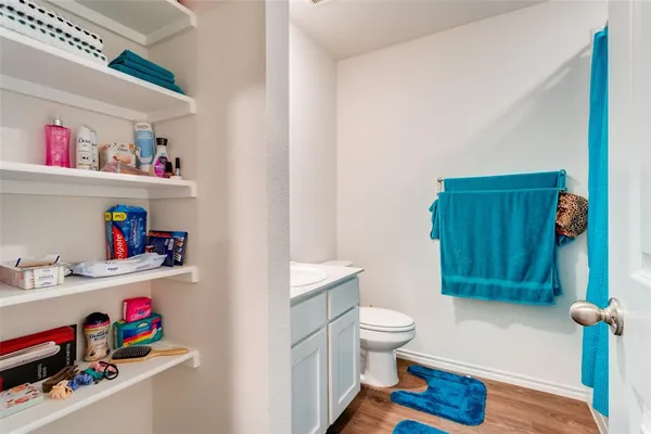a bathroom with a toilet a sink and wooden floor