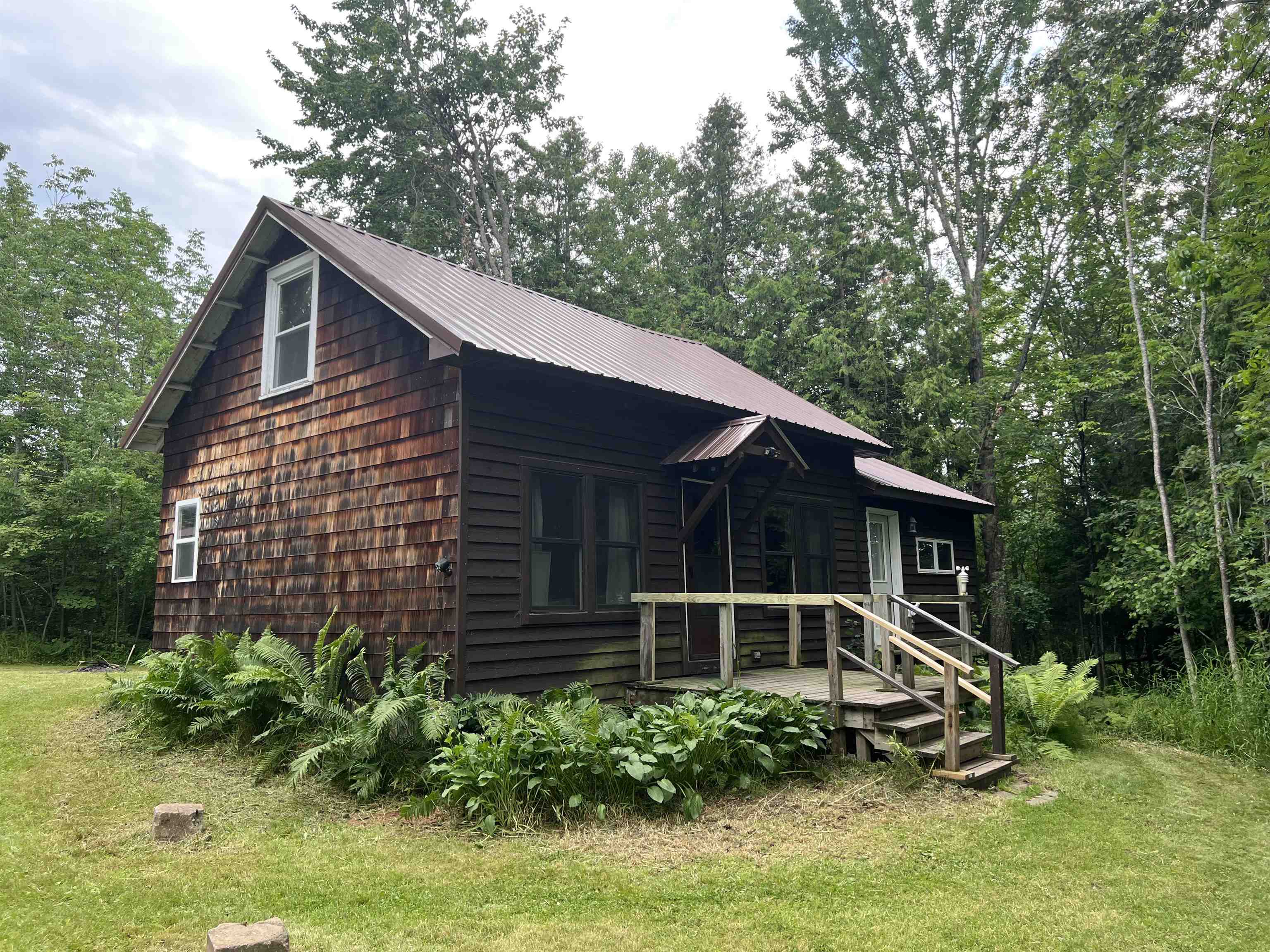 View of front of home with a metal roof and a front lawn