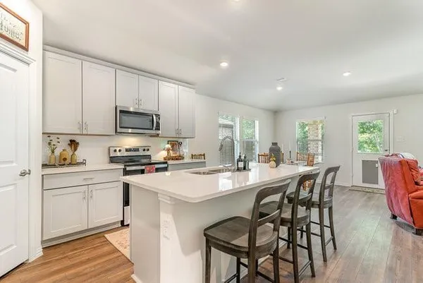 a kitchen with appliances a table and chairs in it