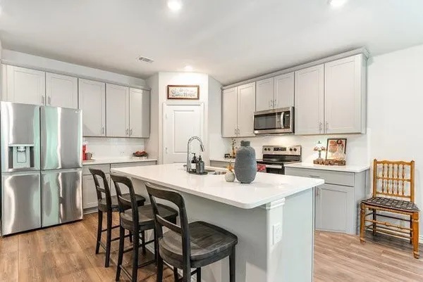 a kitchen with stainless steel appliances granite countertop a table chairs microwave and sink