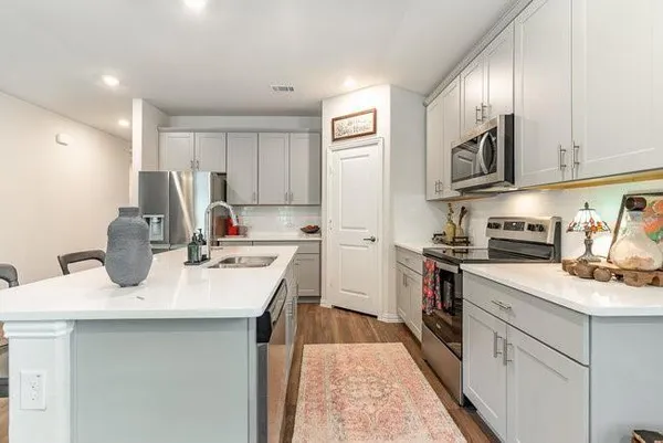 a kitchen with a sink dishwasher a stove a refrigerator and a cabinets with wooden floor