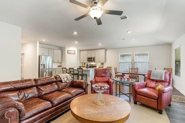 a living room with furniture kitchen view and a chandelier