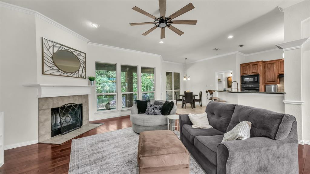 203 Mockingbird Lane Aledo, TX 76008 - Photo 14 of 37 Living area with wood-finish flooring, a ceiling fan, and a fireplace with a stone surround