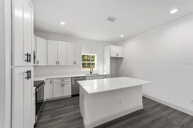 a large kitchen with stainless steel appliances a large counter top and a wooden floors