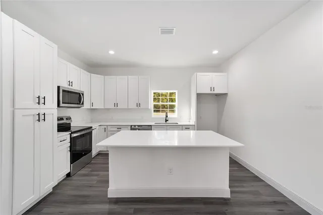 a view with kitchen island a sink wooden floor and stainless steel appliances