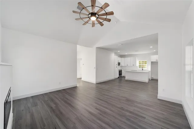 a view of an empty room with a window and a kitchen