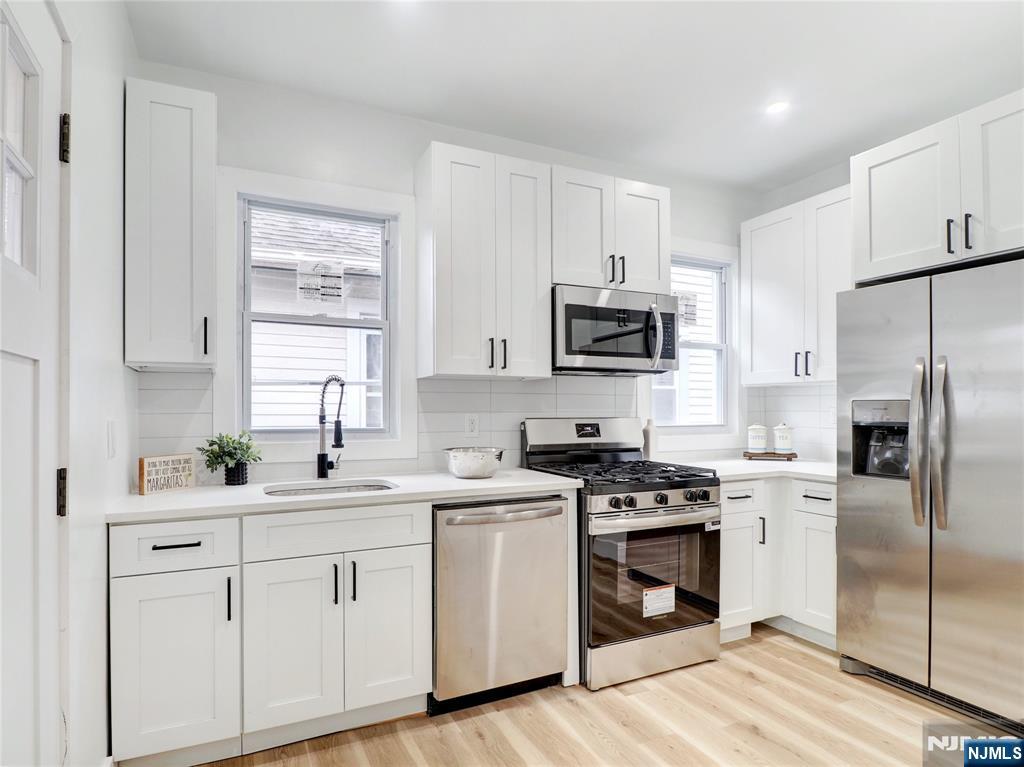 44 Laventhal Avenue Irvington, NJ 07111 - Photo 9 of 26 a kitchen with white cabinets sink and stainless steel appliances