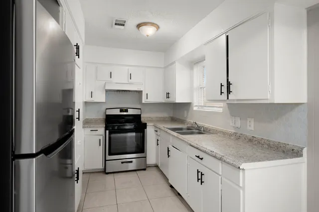 a kitchen with stainless steel appliances granite countertop a stove a sink and a refrigerator