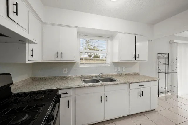 a kitchen with white cabinets sink and appliances