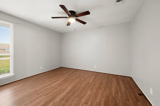 an empty room with wooden floor and windows