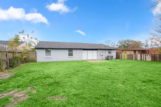 a view of a house with brick walls plants and large tree