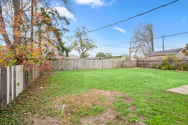 a view of a yard with large tree and wooden fence
