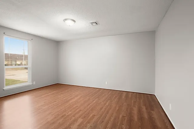 an empty room with wooden floor and windows