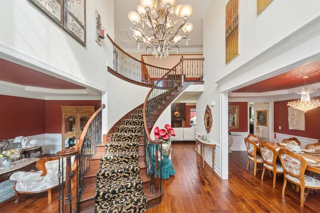 a dining room with wooden floor a chandelier a glass table and chairs