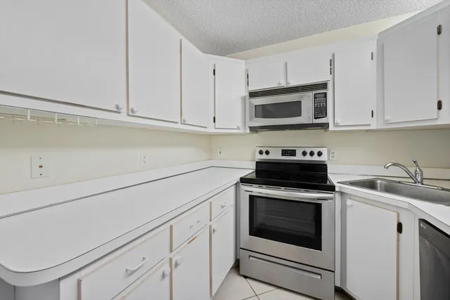 a kitchen with granite countertop white cabinets sink and stainless steel appliances