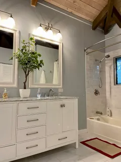 a bathroom with a double vanity sink a mirror a bathtub and shower